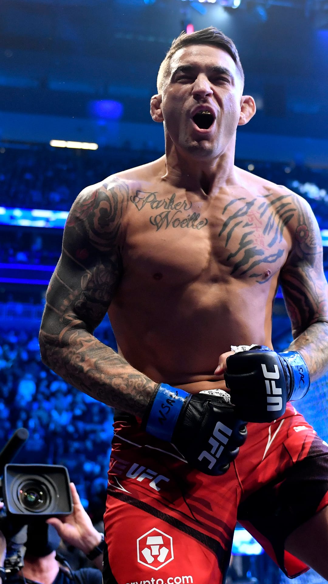Dustin Poirier celebrates a UFC win with tattooed arms raised, wearing gloves in an octagon sports background.