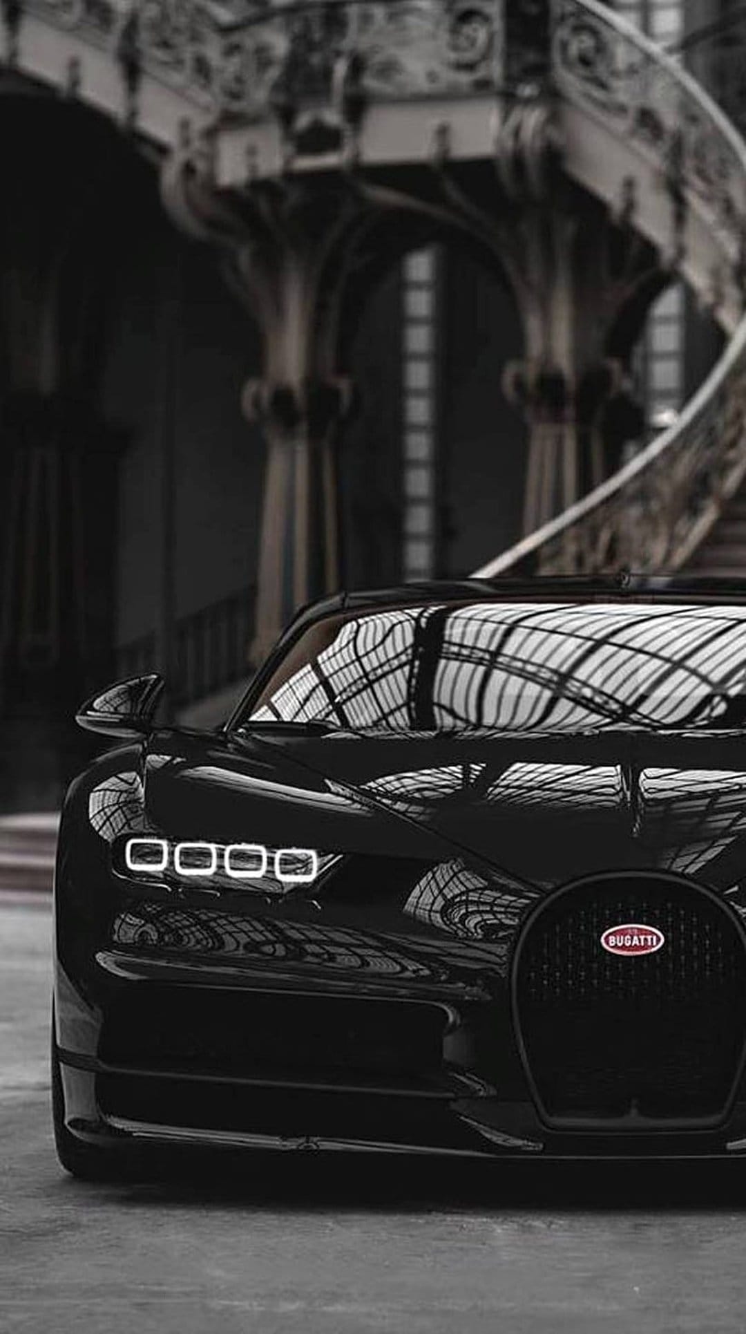 Bugatti Chiron windshield glass reflects light over a dark luxury interior with visible leather seat stitching.