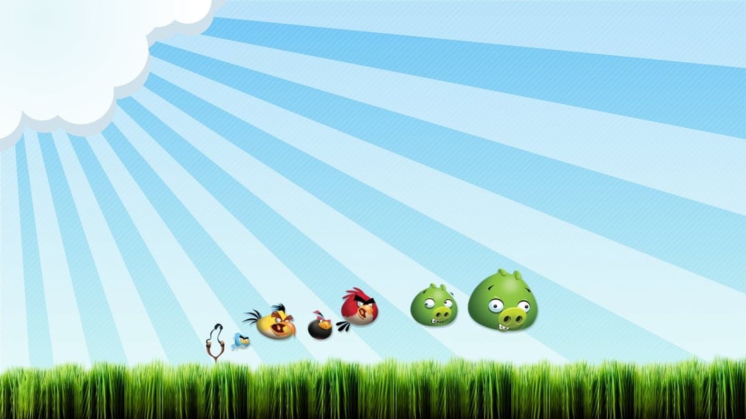 Red, Chuck, and Bomb birds with Green Pigs floating over green grass under a blue sunburst sky with a cloud.