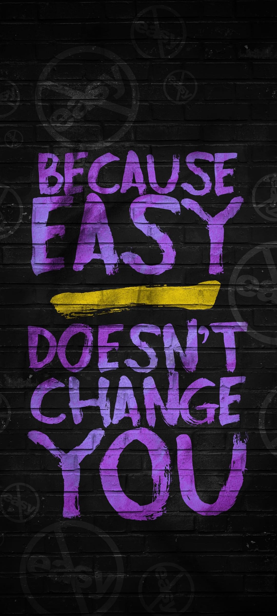 Purple graffiti letters on black bricks read BECAUSE EASY DOESN'T CHANGE YOU with a yellow strike through.