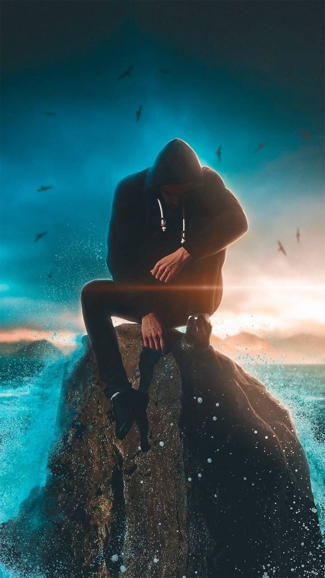 Hooded figure sits on a jagged rock overlooking crashing ocean waves under a gradient orange and blue sky.