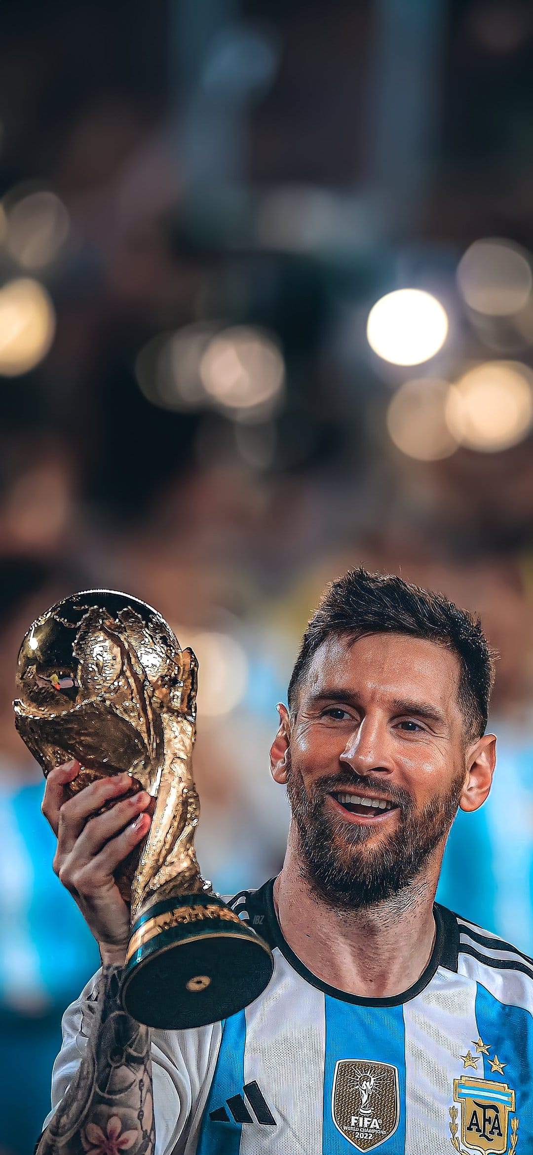 Lionel Messi holding the gold FIFA World Cup trophy while wearing an Argentina jersey in a crowded stadium.