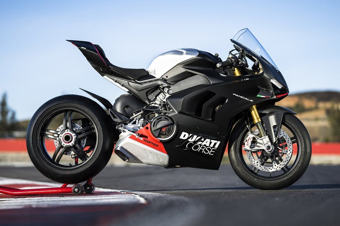 Ducati Panigale V4 SP2 motorcycle in matte black with red accents on a racetrack paddock stand under a clear sky.