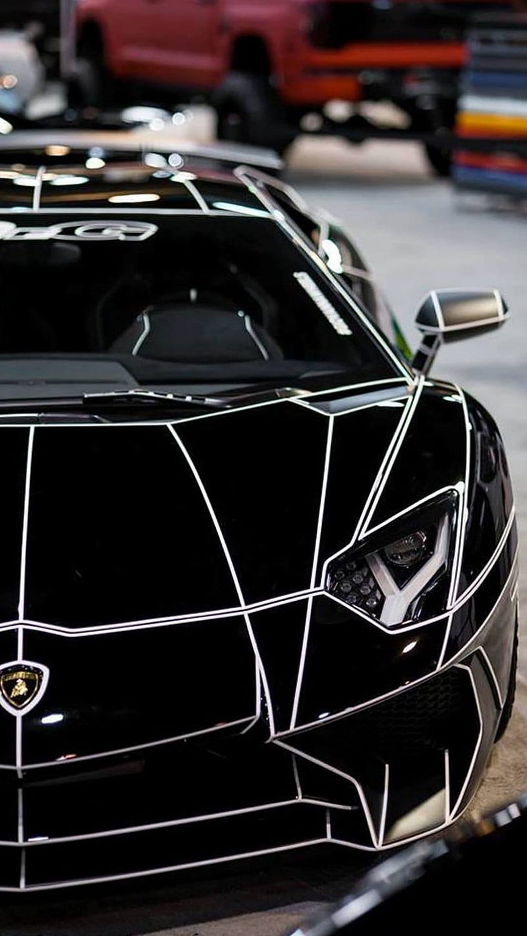 Black Lamborghini sports car with white geometric stripes and LED headlights angled for a vertical phone screen.