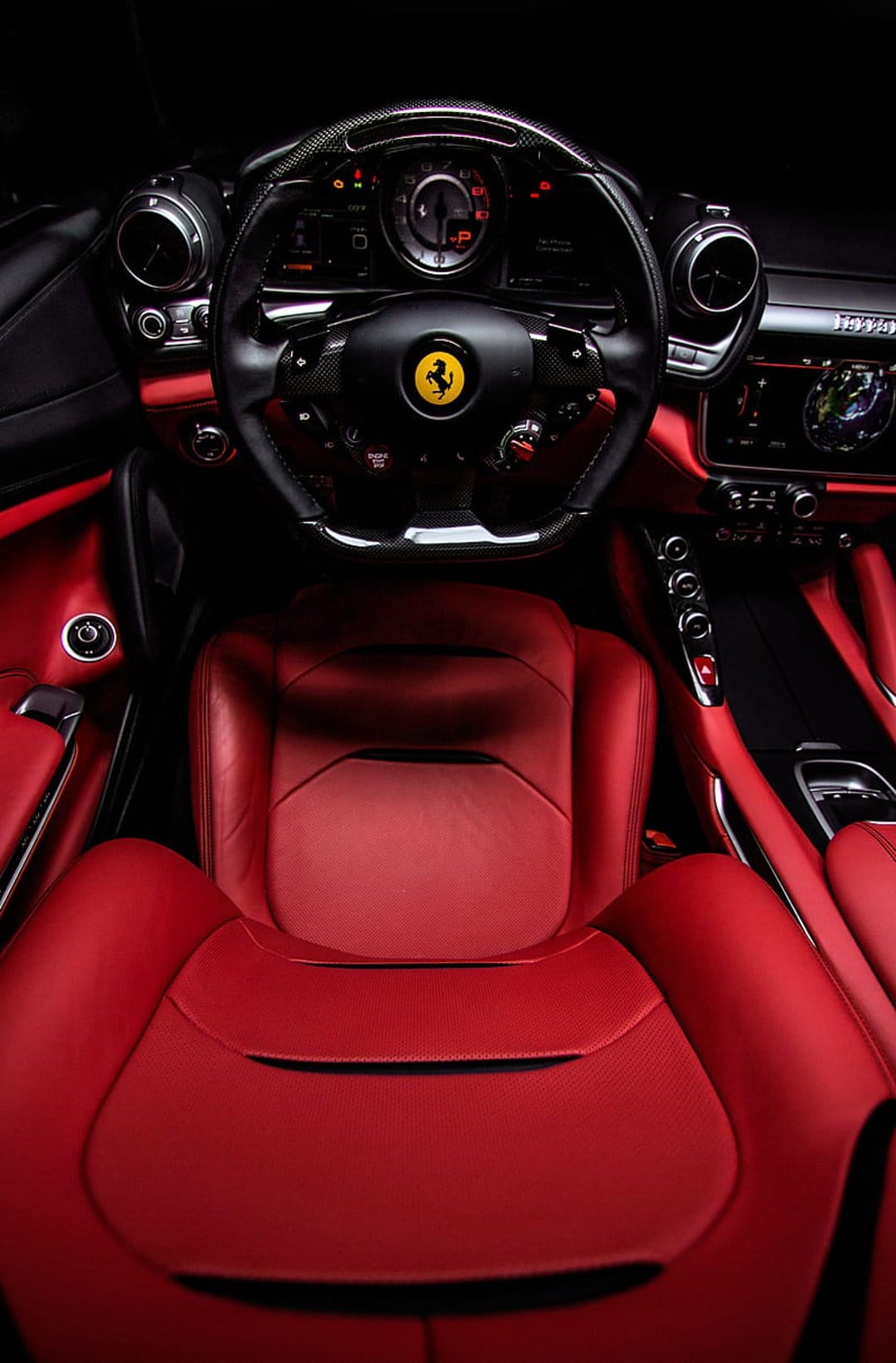 Ferrari steering wheel with logo and red leather seats inside a high-performance Italian supercar cabin.