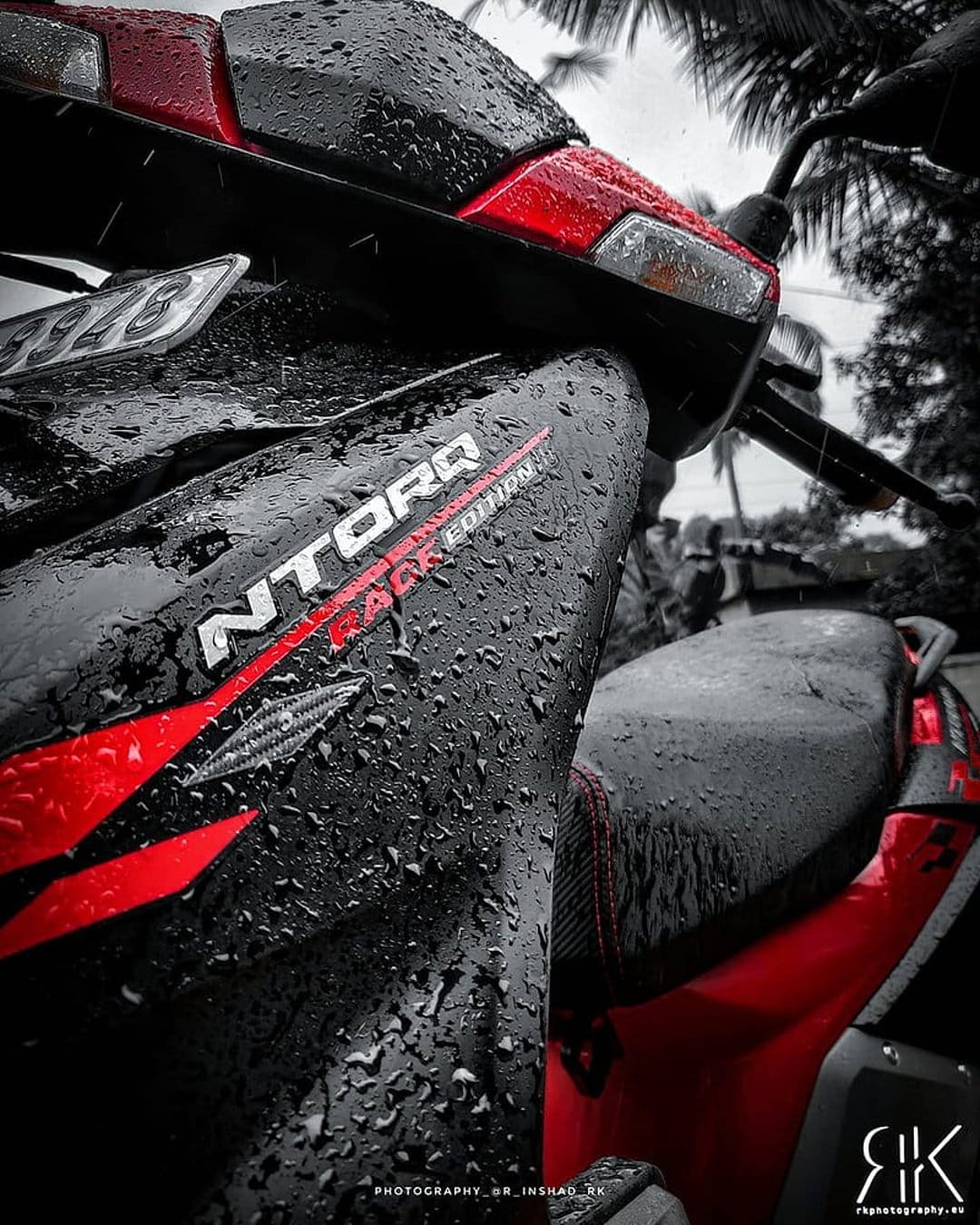 Red and black sport scooter with rain droplets on its body panels and NTORQ logo in a close-up macro shot.