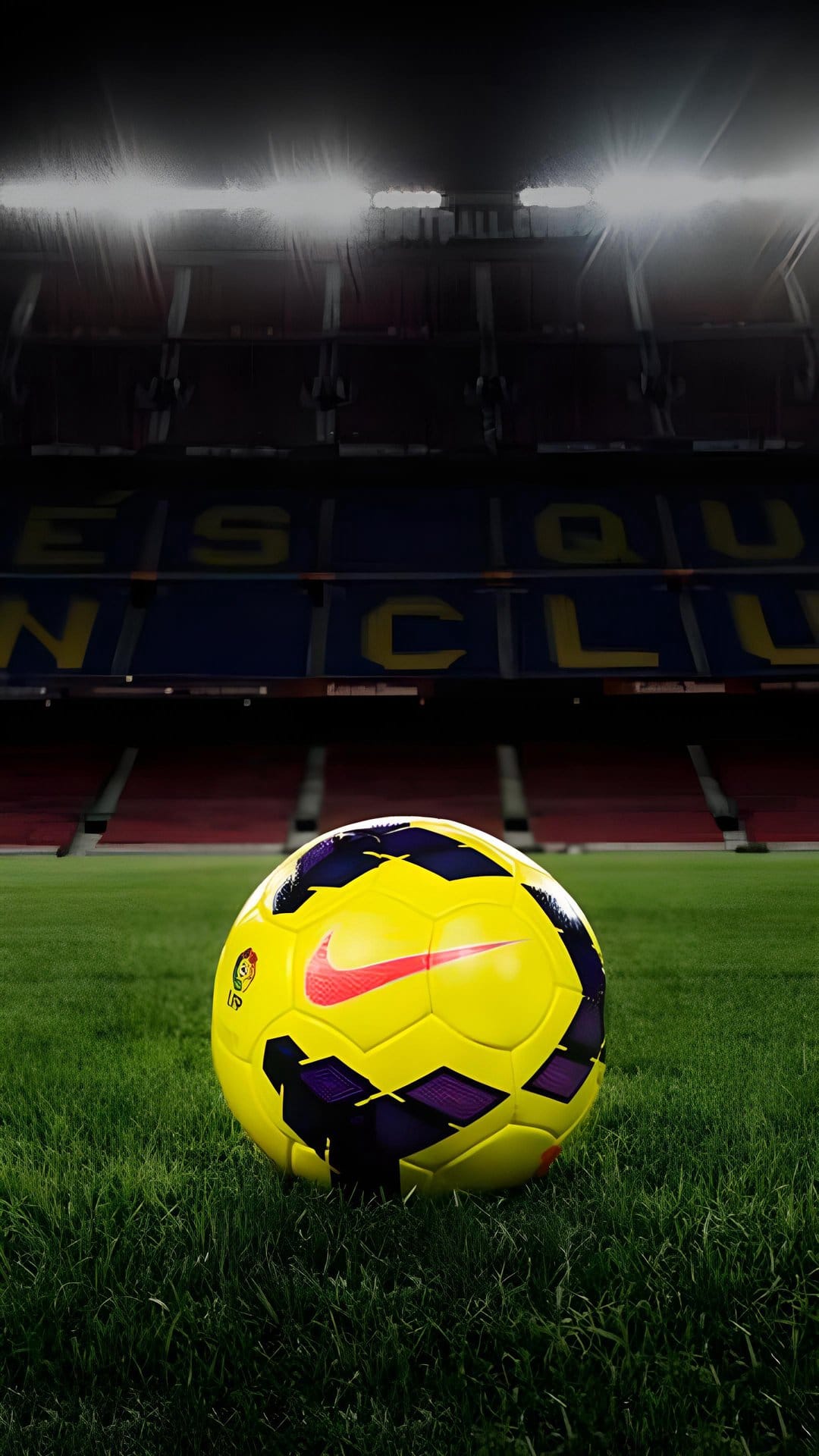 Yellow and purple soccer ball on green grass with the FC Barcelona stadium seating and lights in the background.