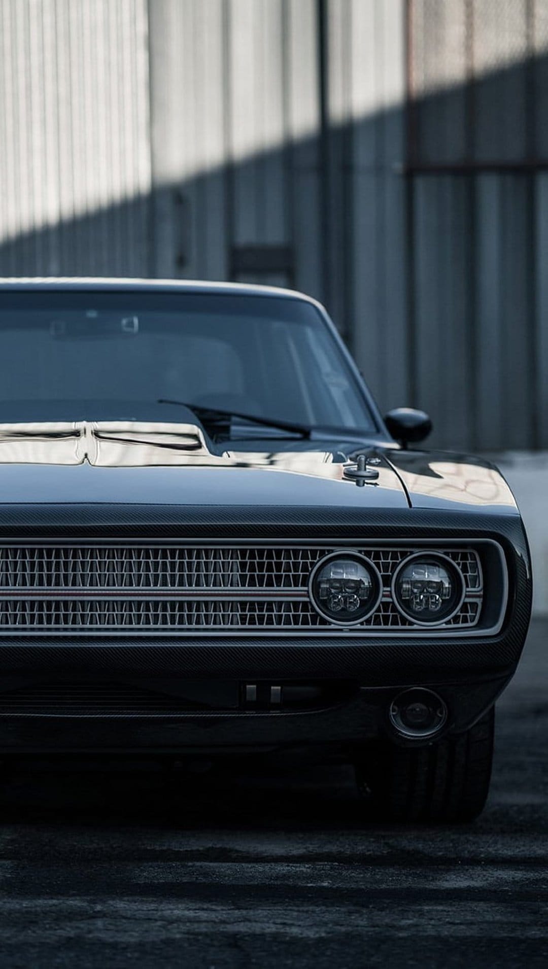Black Dodge Charger front grille and dual round headlights illuminated against a dark, textured background.