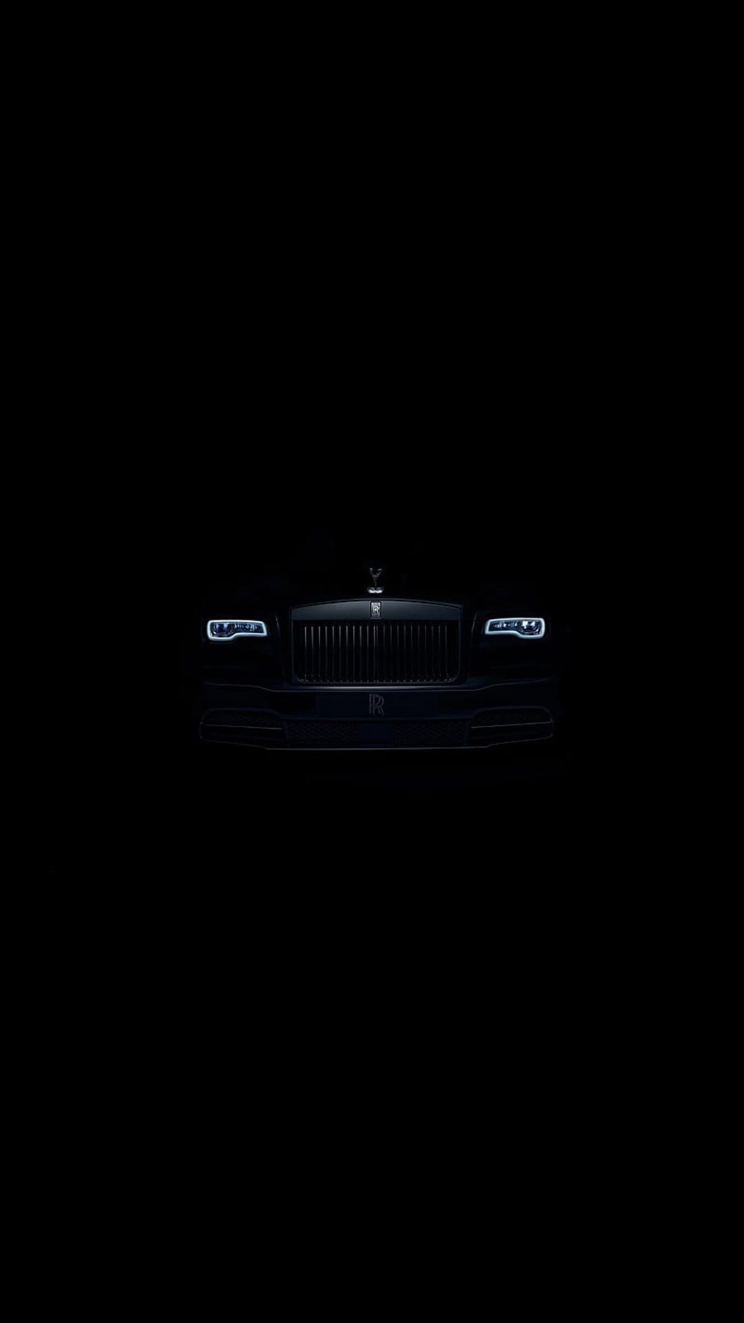 Black Rolls-Royce Phantom front grille and LED headlights with the Spirit of Ecstasy ornament in low light.