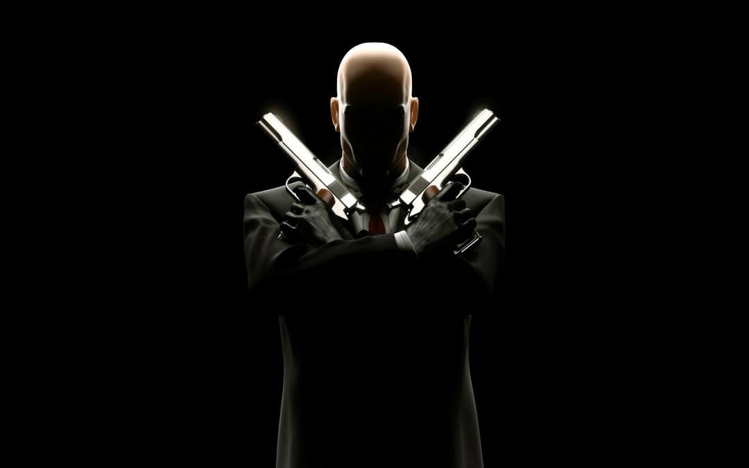Agent 47 in a black suit with crossed silver pistols against a dark background with sharp rim lighting.