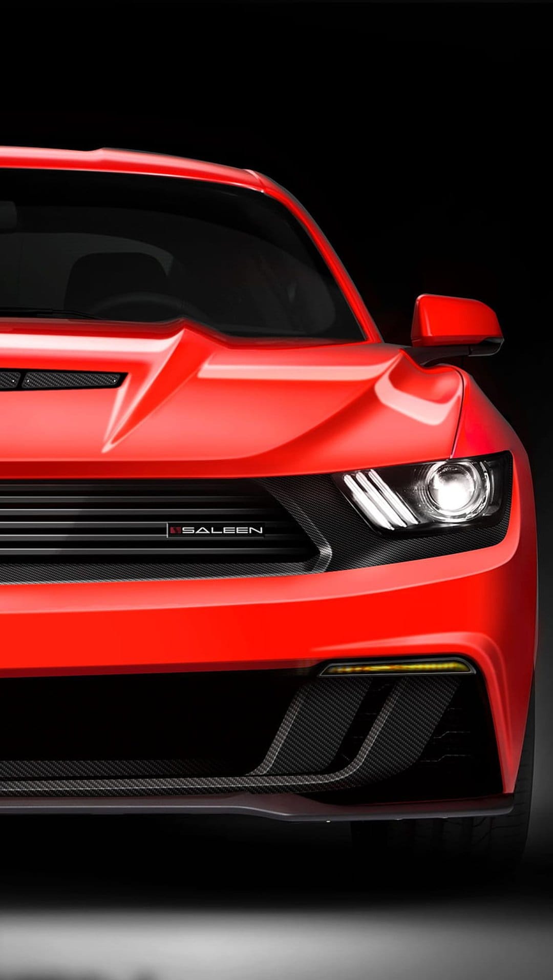 Red Saleen Mustang front view with a black grille, sharp headlights, and carbon fiber accents on a dark backdrop.