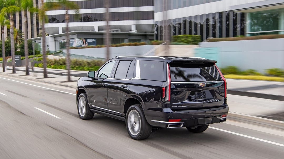 Black Cadillac Escalade driving through a modern urban landscape with motion blur and glass buildings.