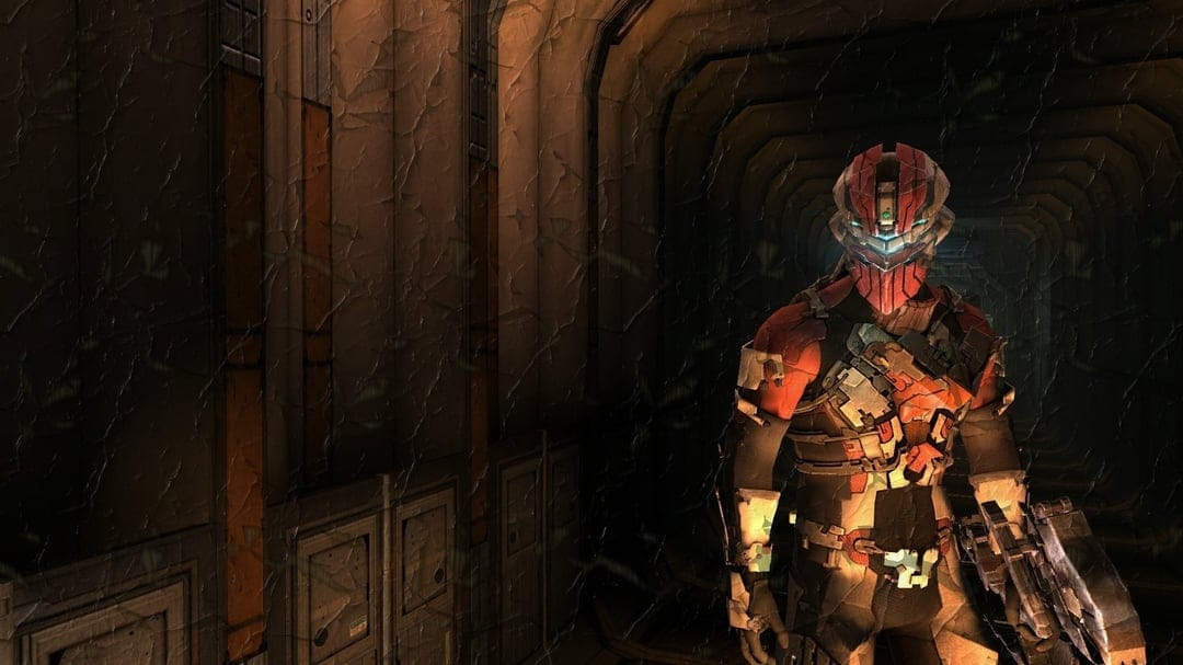 Isaac Clarke in red and grey futuristic armor stands in a dark metallic corridor with warm side lighting.
