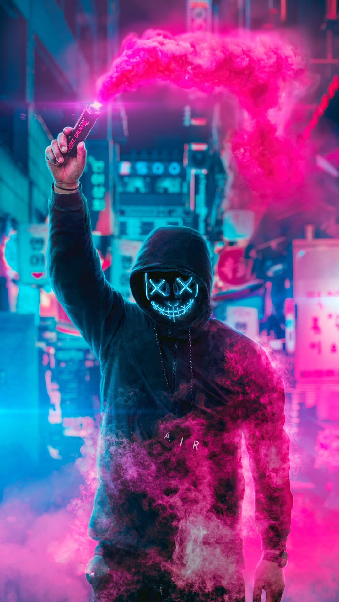 Masked person holds a pink smoke flare while wearing a glowing blue mask against a blurred neon city background.