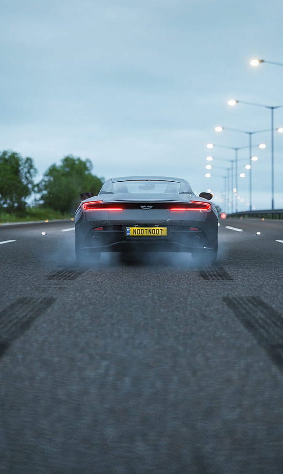 Dark Aston Martin sports car drifting on a highway with white tire smoke and glowing red taillights at dusk.