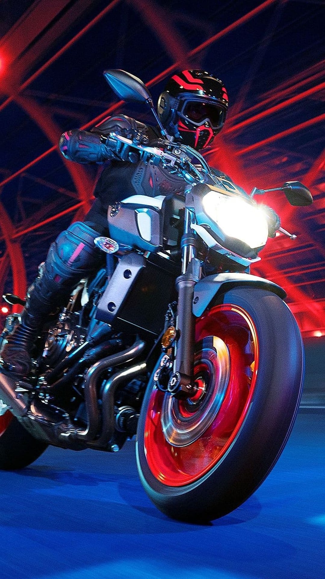 Motorcycle rider in a red helmet leans through a futuristic tunnel with blurred blue and crimson neon light trails.