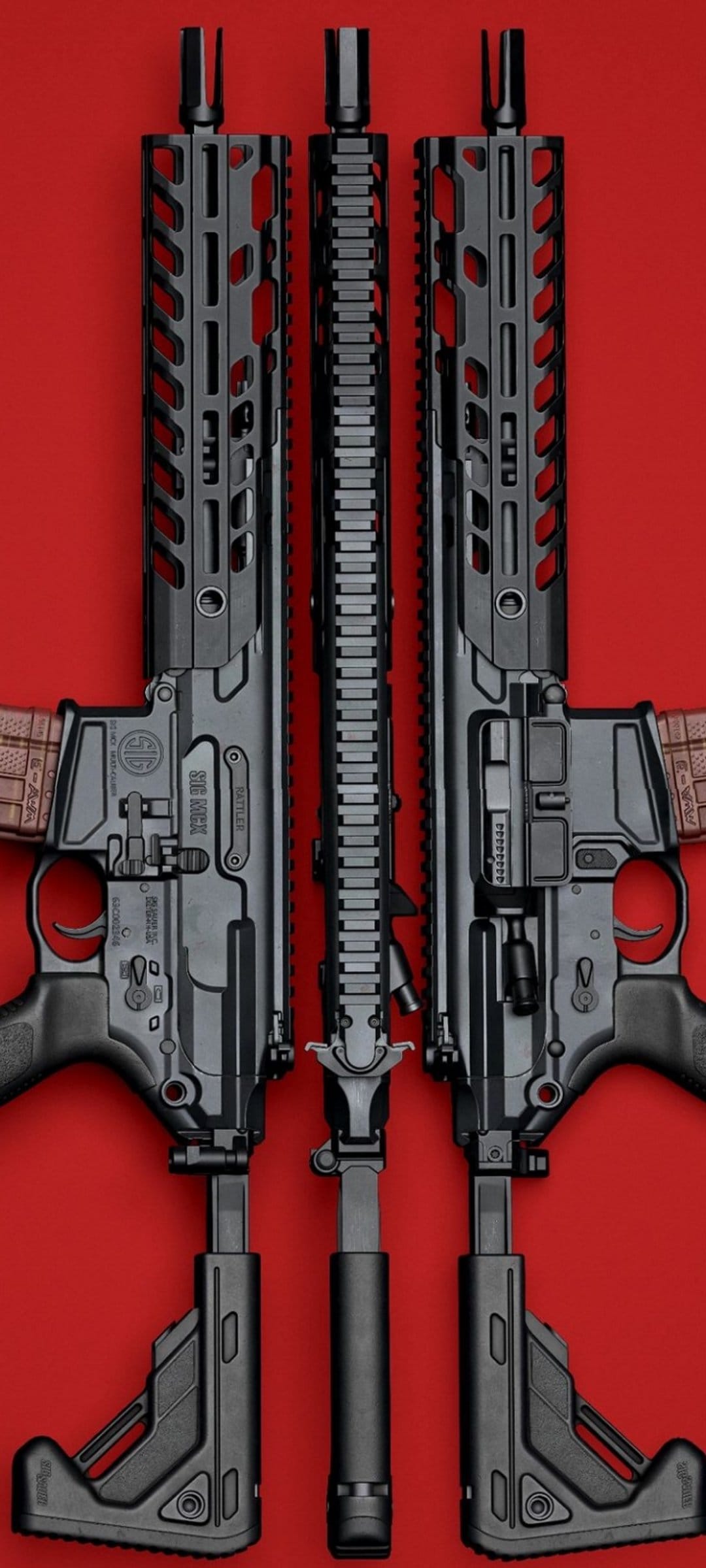 Three black tactical rifles arranged vertically on a solid red surface showing rail systems and metal receivers.