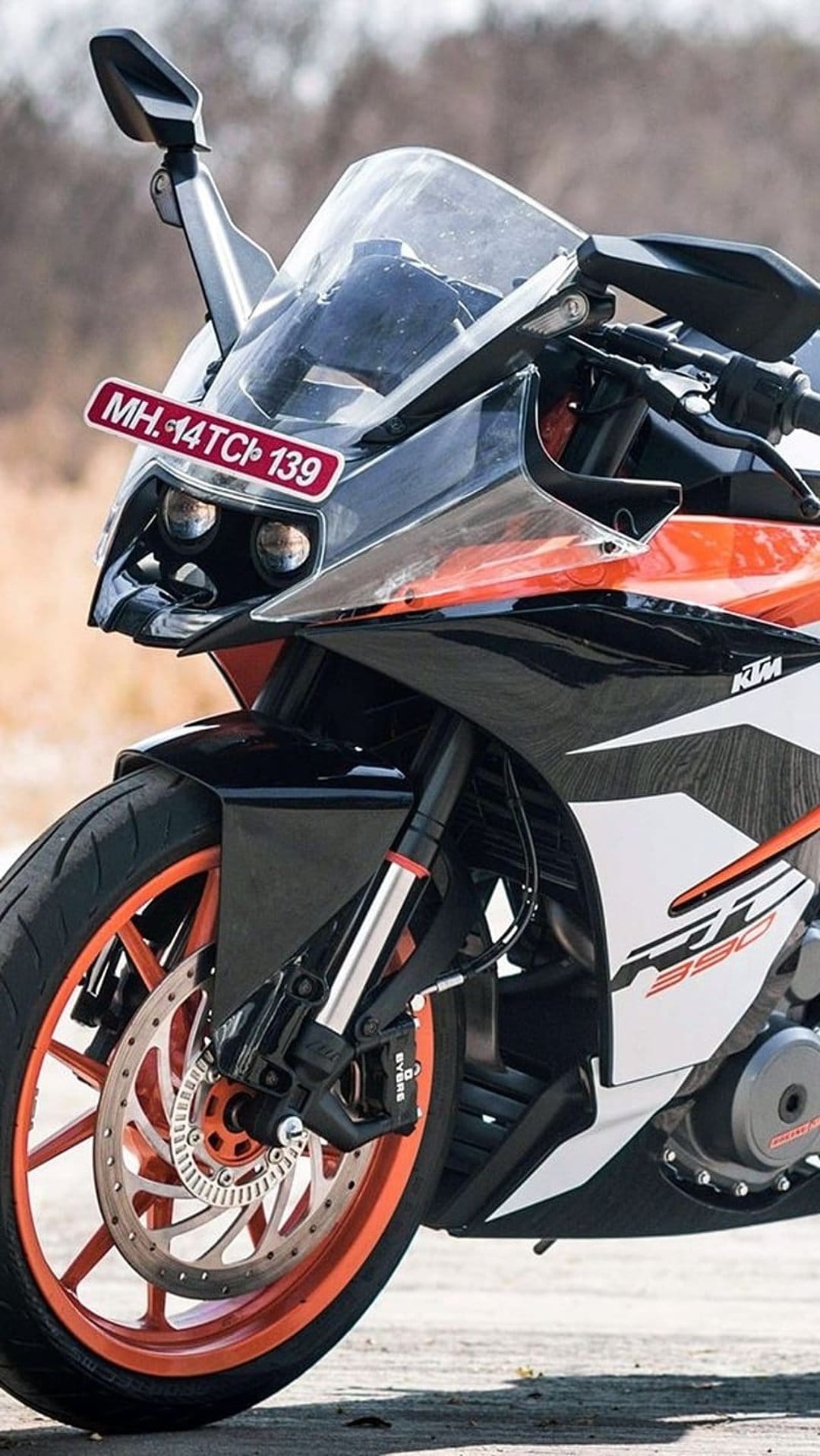KTM RC 390 motorcycle front end featuring twin headlights, orange alloy wheels, and a black aerodynamic fairing.