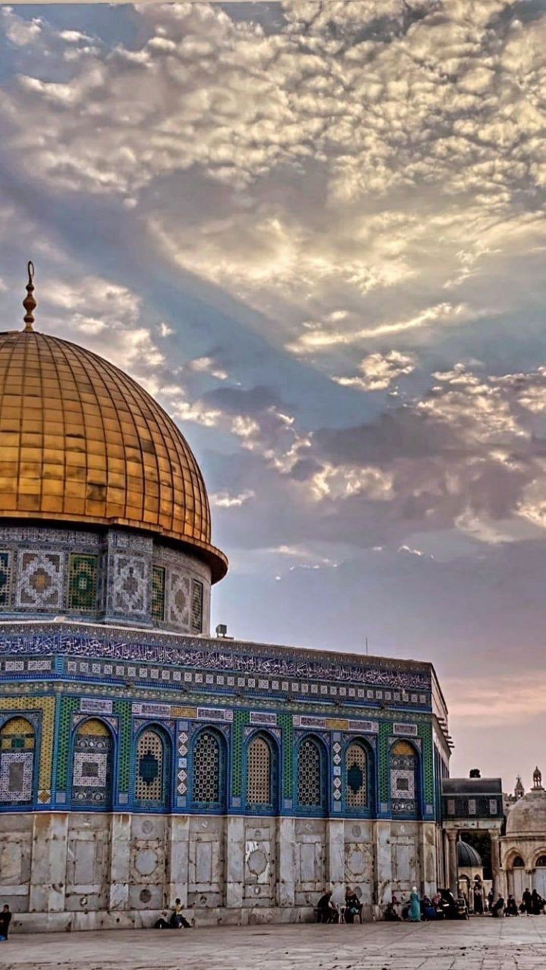 Dome of the Rock stands under swirling clouds with intricate blue tilework and a golden roof in Jerusalem.