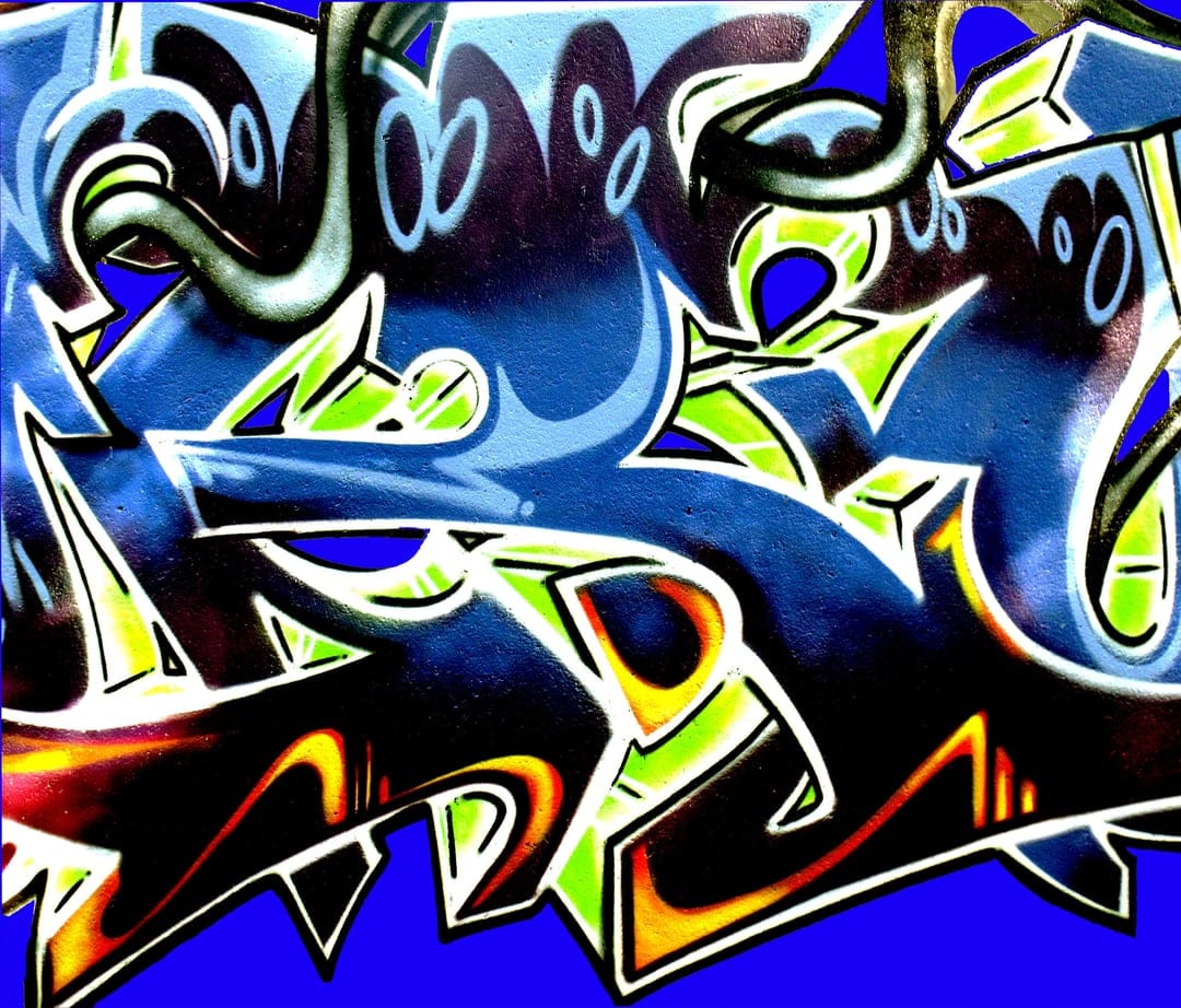 Electric green and blue graffiti letters with sharp angles and orange paint splatters across the frame.
