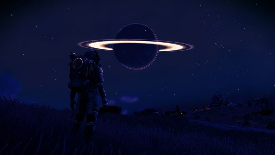 Astronaut standing on a grassy hill looking at a large glowing ringed planet in a dark starry night sky.