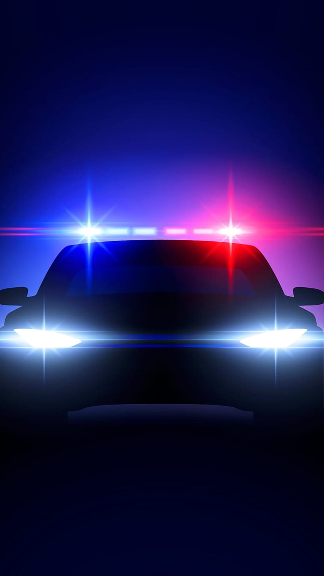 Police car front view at night with flashing blue and red emergency lights and bright glowing headlights.