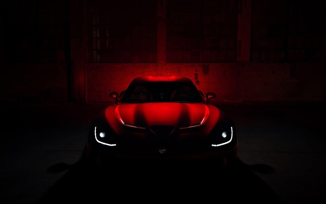 Red Dodge Viper front view with glowing white LED headlights in a dark industrial space with red lighting.