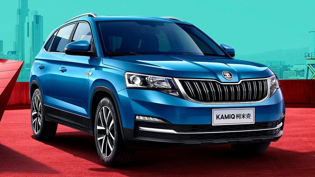 Blue Skoda Kamiq SUV on a red ground with a teal city silhouette and bright sky in the background.