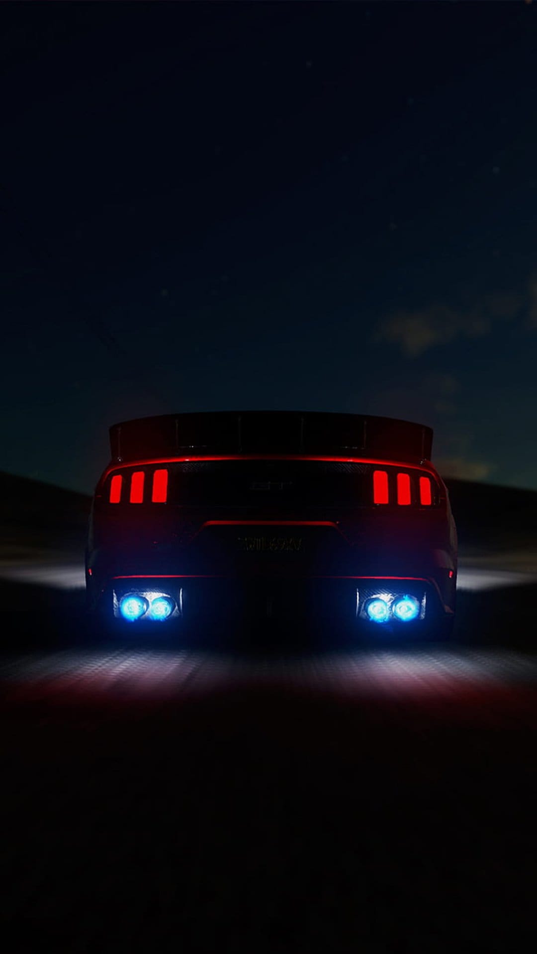 Ford Mustang GT rear view at night featuring glowing red tri-bar taillights and bright blue exhaust flames.
