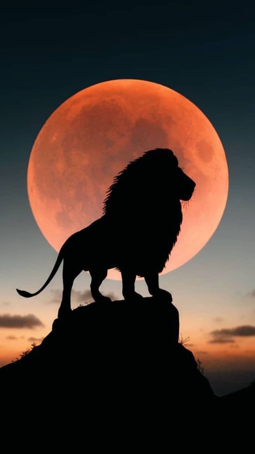 Lion silhouette standing on a rocky peak before a massive glowing red blood moon in a dark twilight sky.