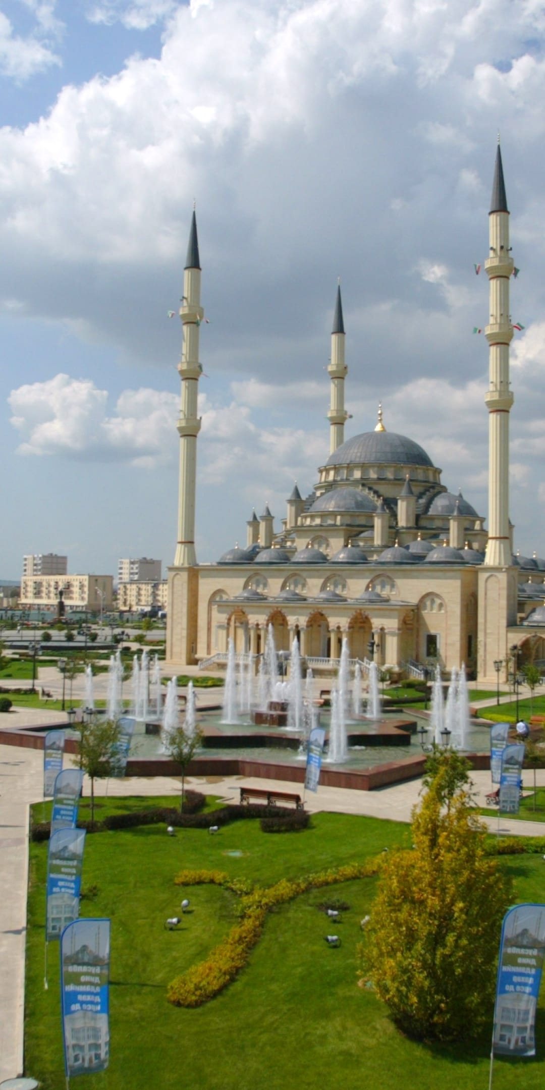 Heart of Chechnya Mosque with four tall minarets and central dome behind tiered water fountains and green gardens.