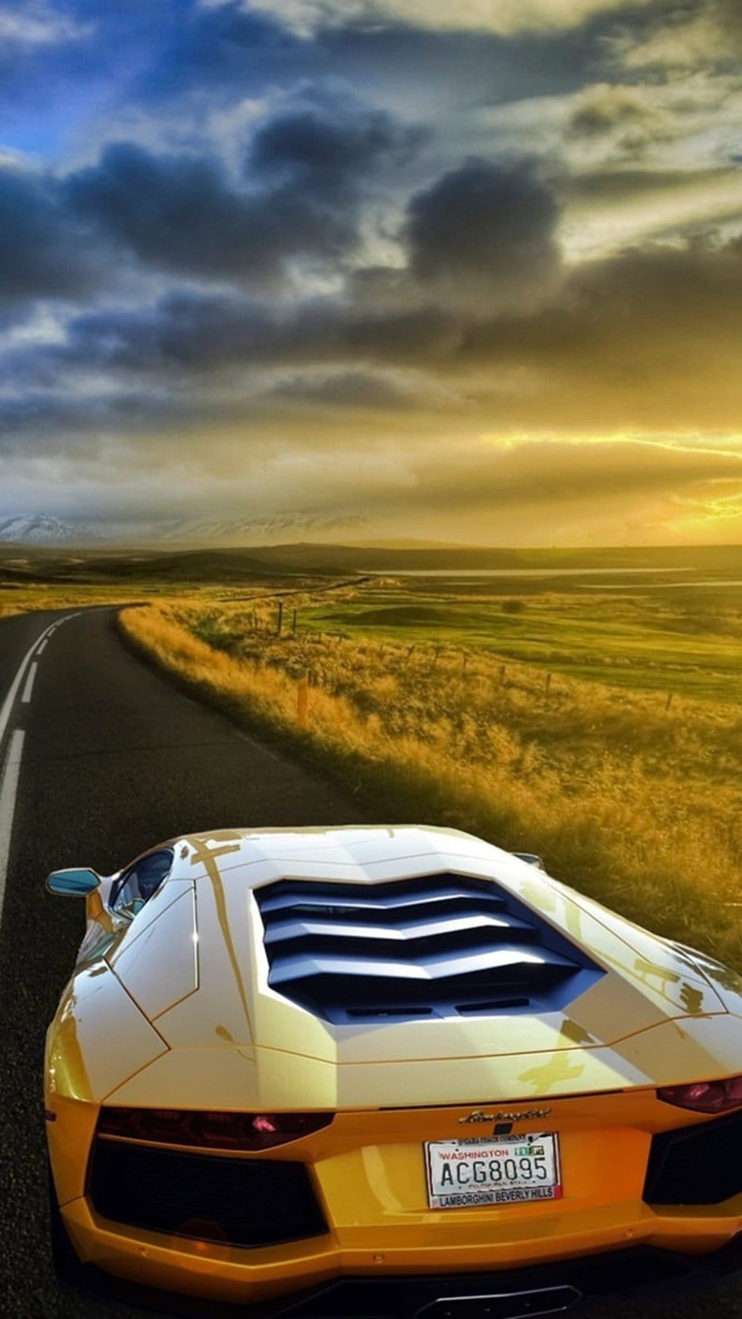 Yellow Lamborghini Aventador on a remote Iceland road during golden hour under a dramatic stormy sky background.