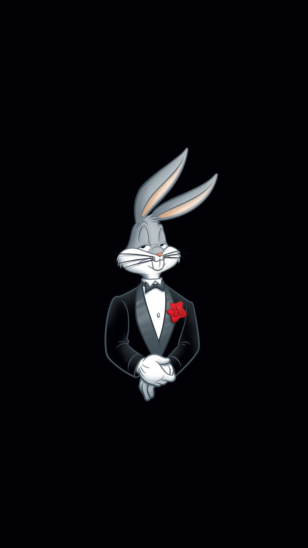 Bugs Bunny wears a formal black tuxedo with a red rose on the lapel while standing against a dark background.