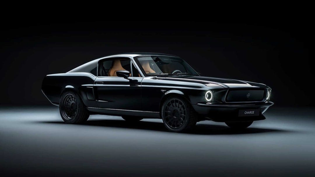 All-black electric classic muscle car with tan interior in a dark studio with dramatic lighting.