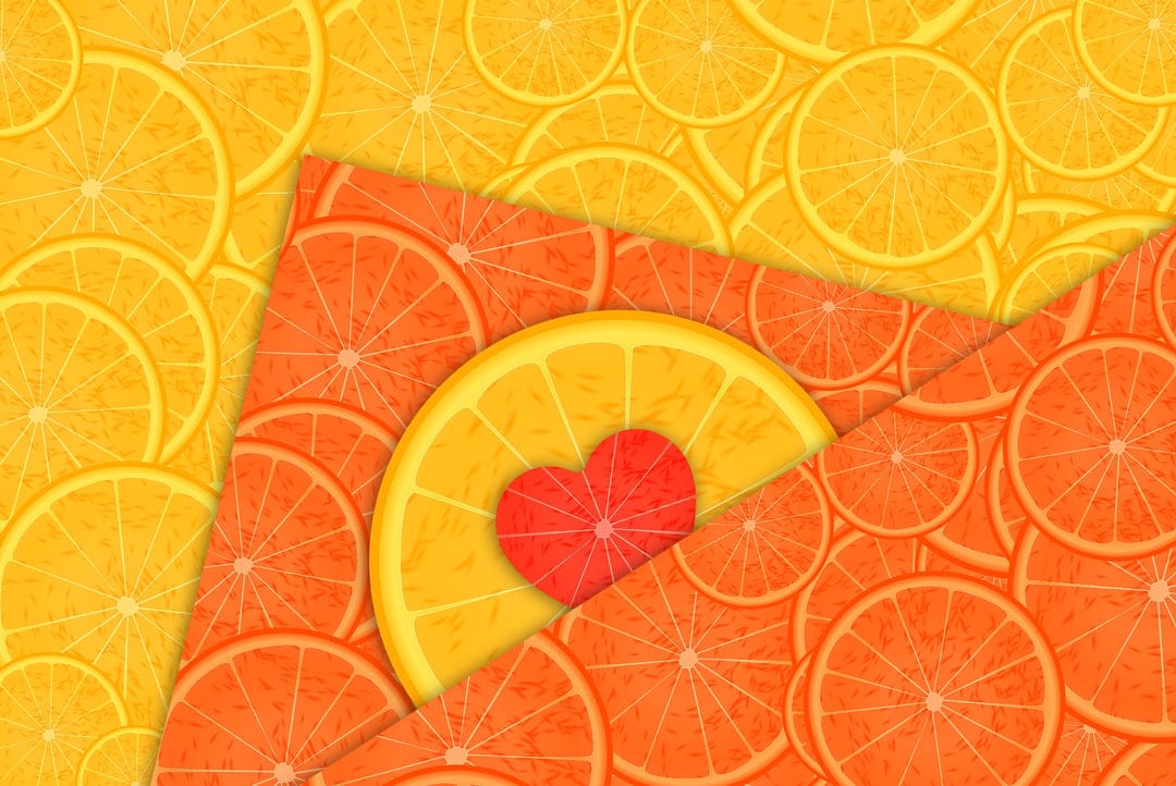 Vibrant orange and grapefruit slices overlap around a small red heart symbol in a refreshing summer composition.