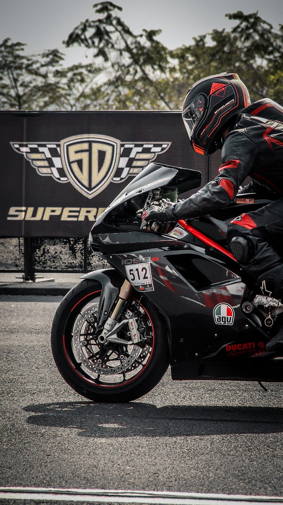 Ducati racing motorcycle with rider number 512 leaning into a turn on a paved track with SD Superbike logo behind.