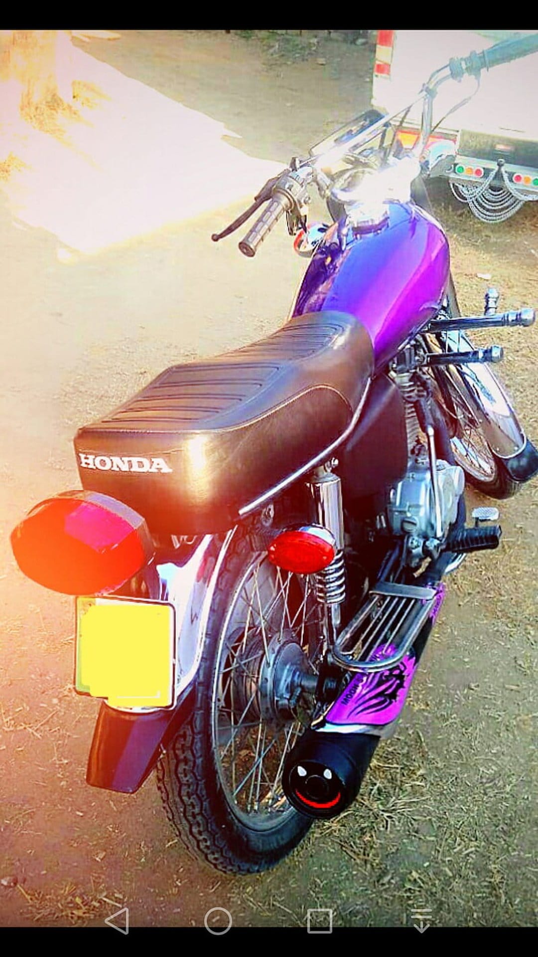 Purple Honda motorcycle with a smiley-face exhaust tip, chrome accents, and leather seat with a visible logo.