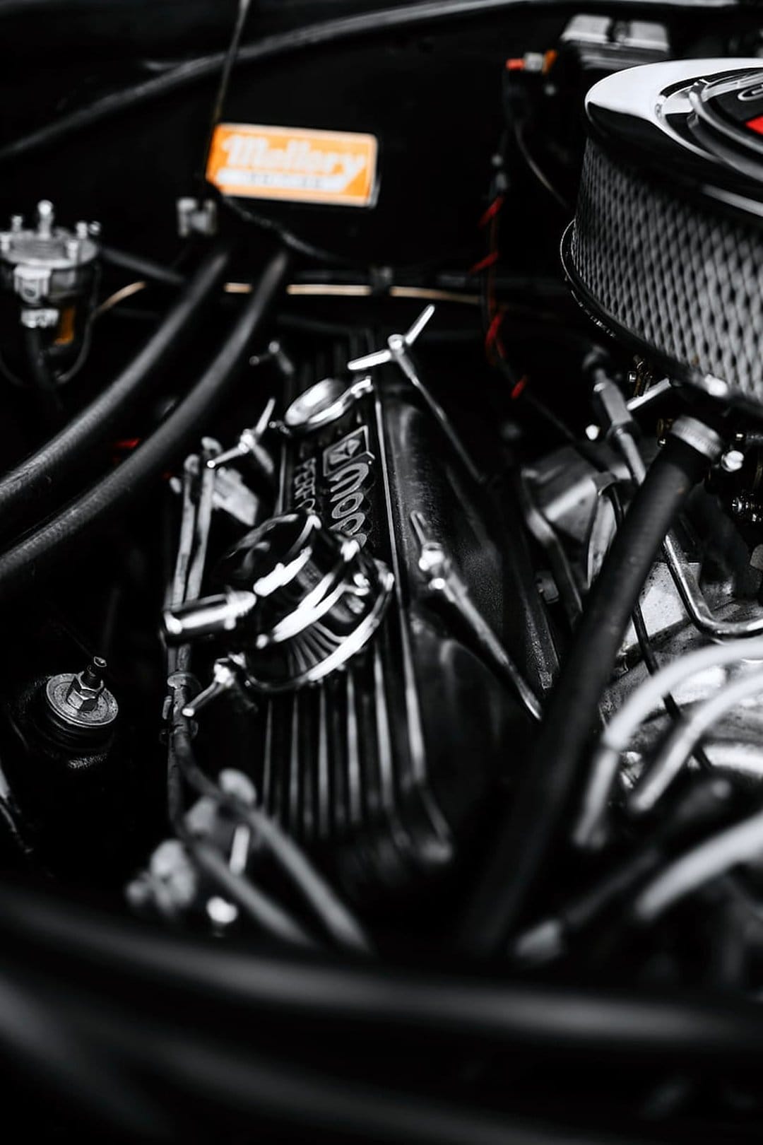 Chrome Mopar valve cover with a Holley label features polished metal textures and intricate engine components.