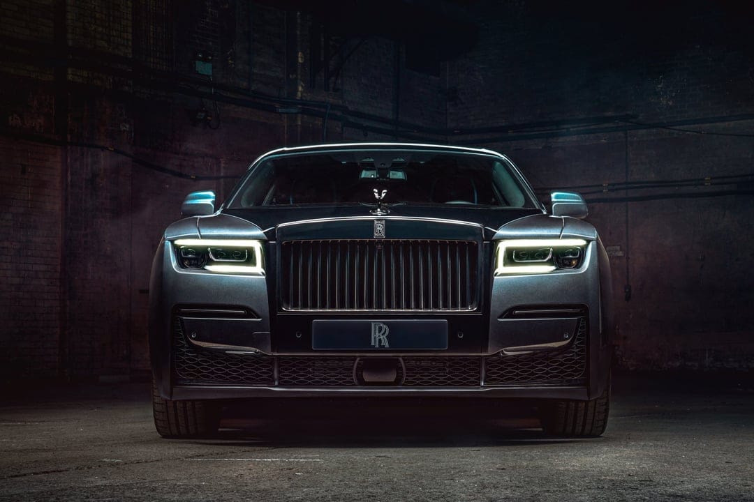 Rolls-Royce Ghost front view with glowing white LED headlights in a dark, industrial brick garage environment.