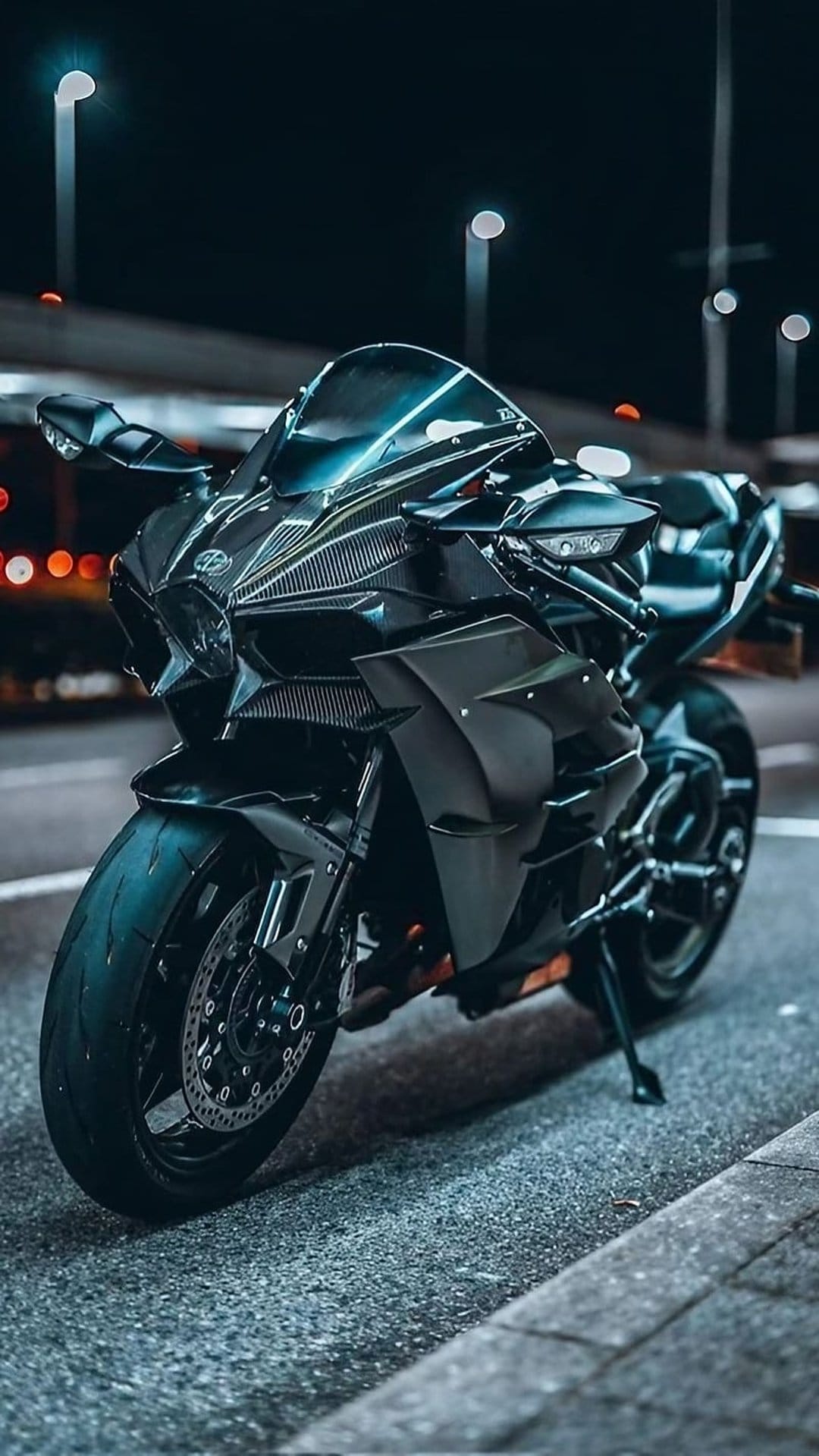 Black sport motorcycle parked on a wet city street at night with glowing bokeh lights reflecting on the pavement.