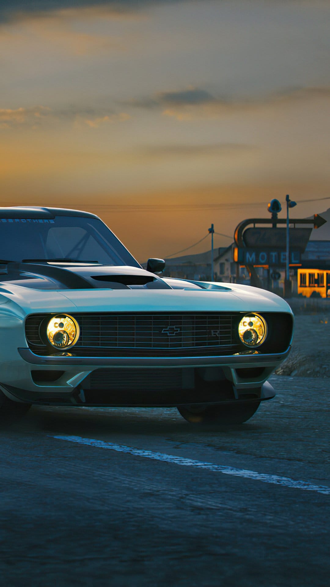 Front view of a white custom Camaro with yellow headlights on a desert road at sunset near a motel sign.