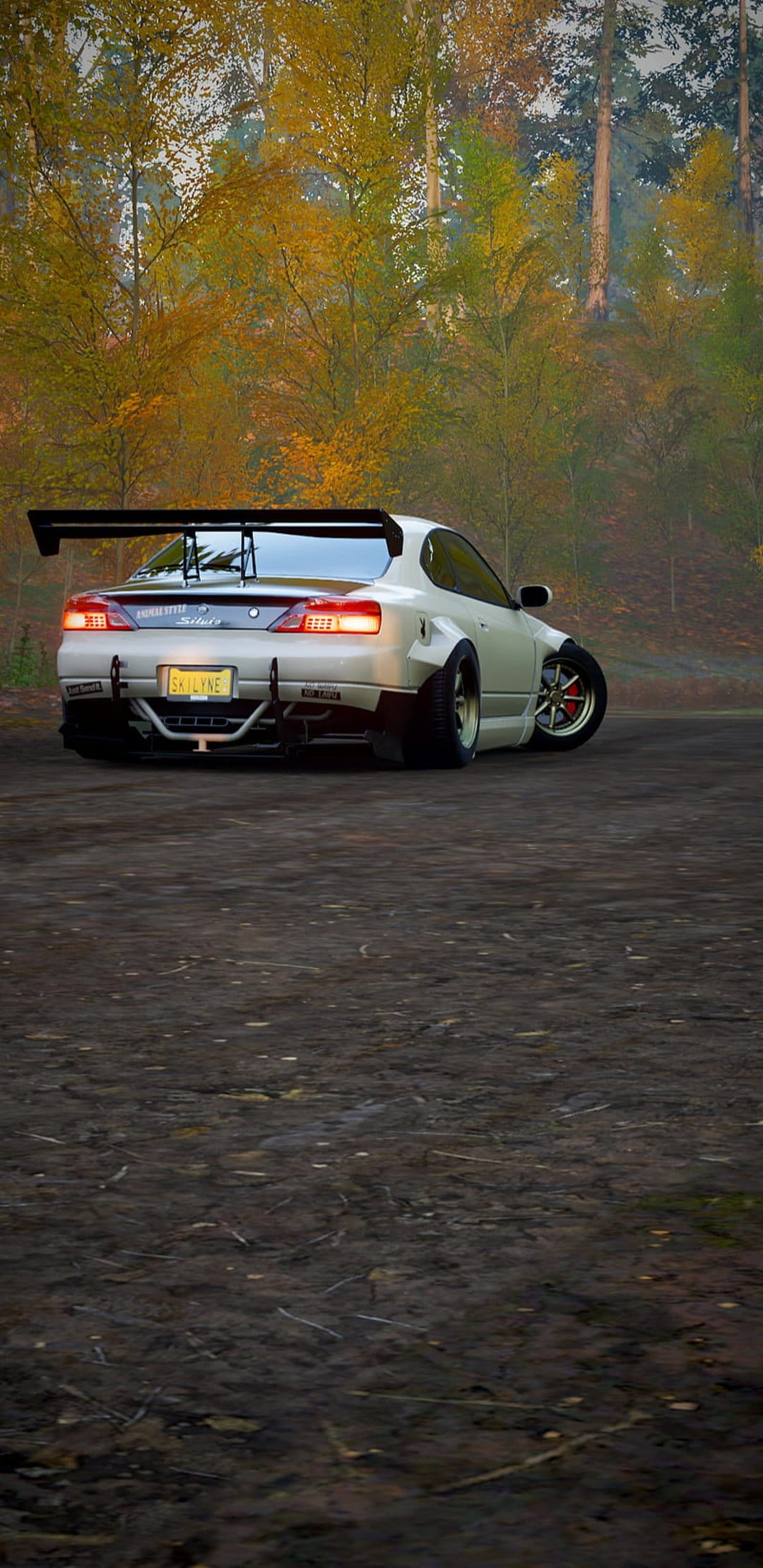 White sports car with a large rear spoiler parked on a dirt path surrounded by orange and yellow autumn trees.