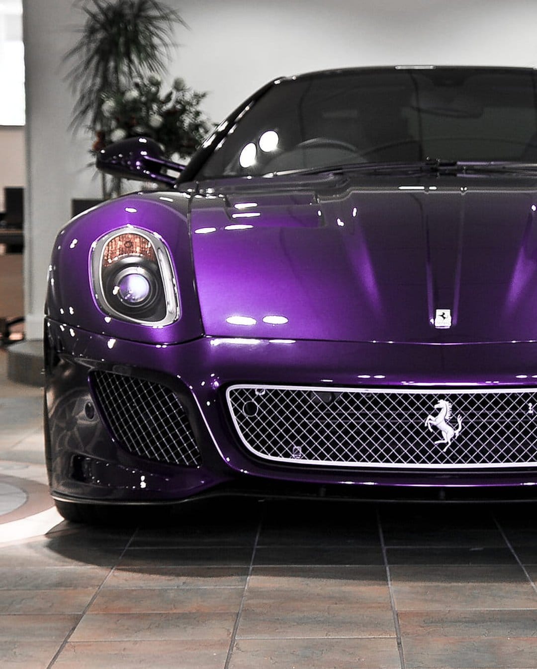 Purple Ferrari front grille and LED headlights in a showroom, showing the horse emblem on diamond mesh.