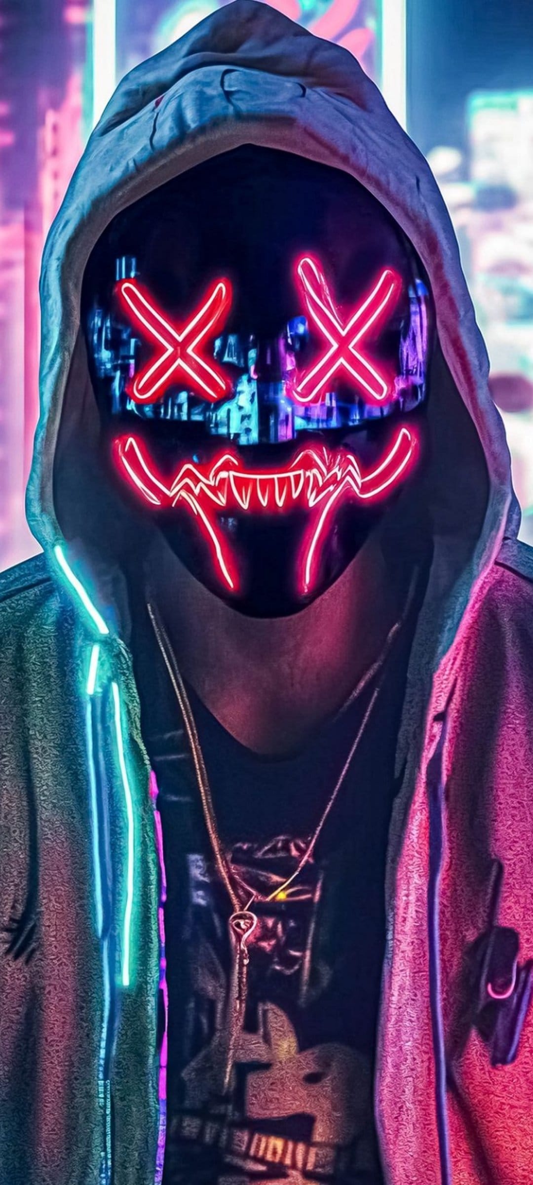 Person in a black hoodie wears a glowing red X mask and silver key necklace against blurred city night lights.