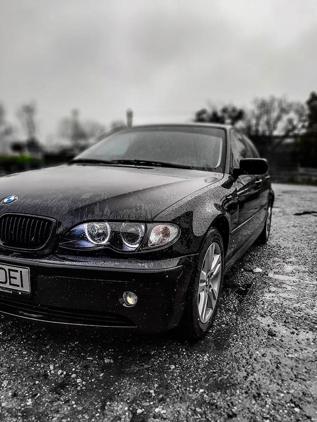 Black BMW E46 coupe with rain droplets on its surface during a moody, desaturated evening car photoshoot.