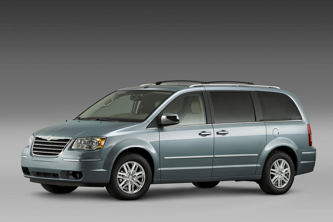 Metallic silver Chrysler Town & Country minivan with chrome accents and alloy wheels on a gray background.
