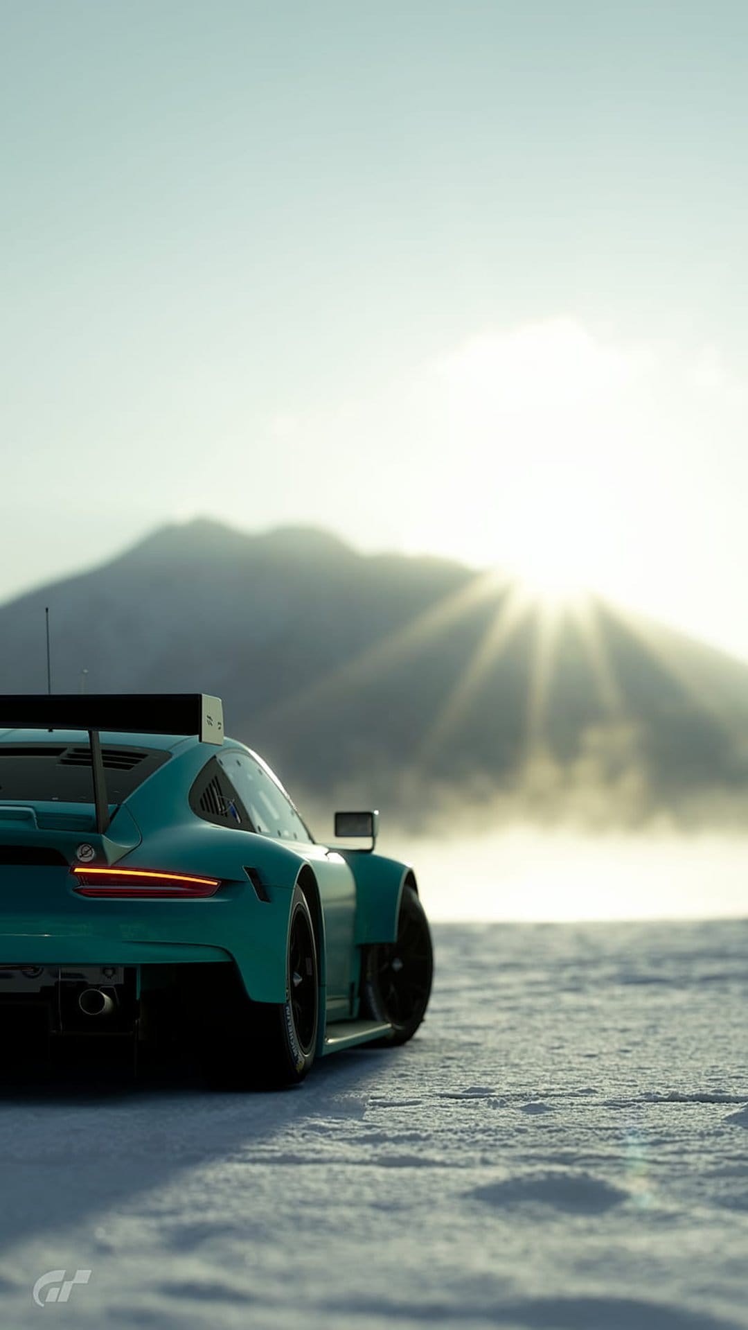Teal Porsche GT race car rear view on a snowy track with sunbeams breaking through misty mountains at sunrise.