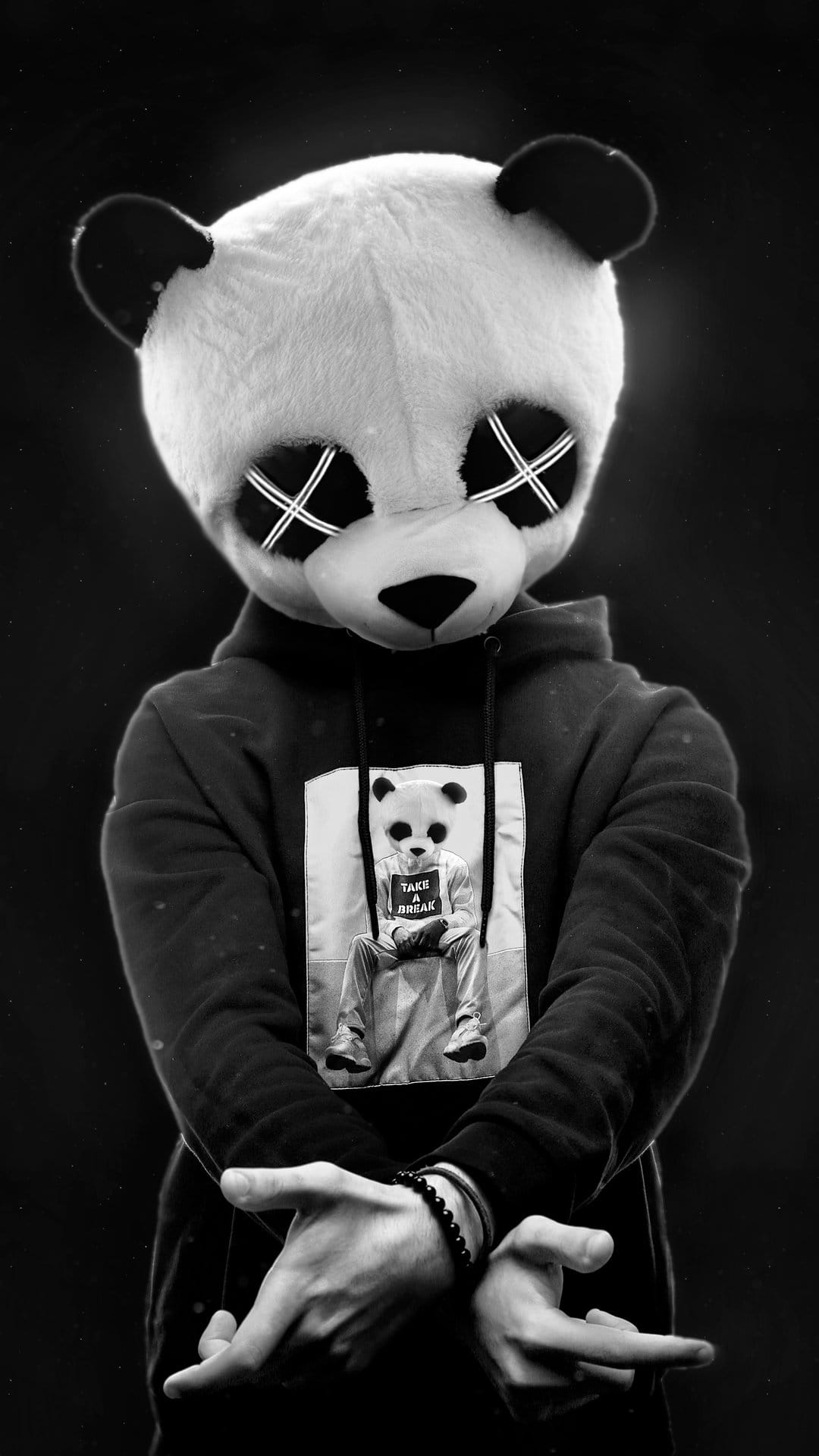 Person in a cross-eyed panda mask wears a graphic streetwear hoodie and beaded bracelets in black and white.