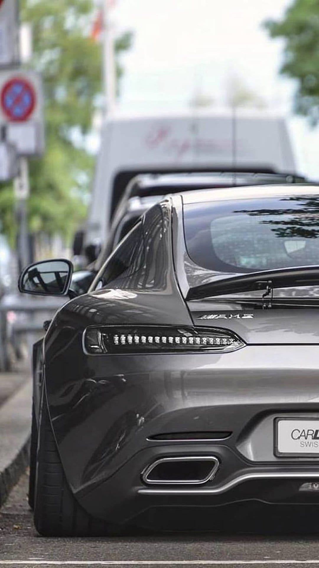 Mercedes-AMG GT R rear view with red LED taillights, a large black diffuser, and twin exhaust on a city street.