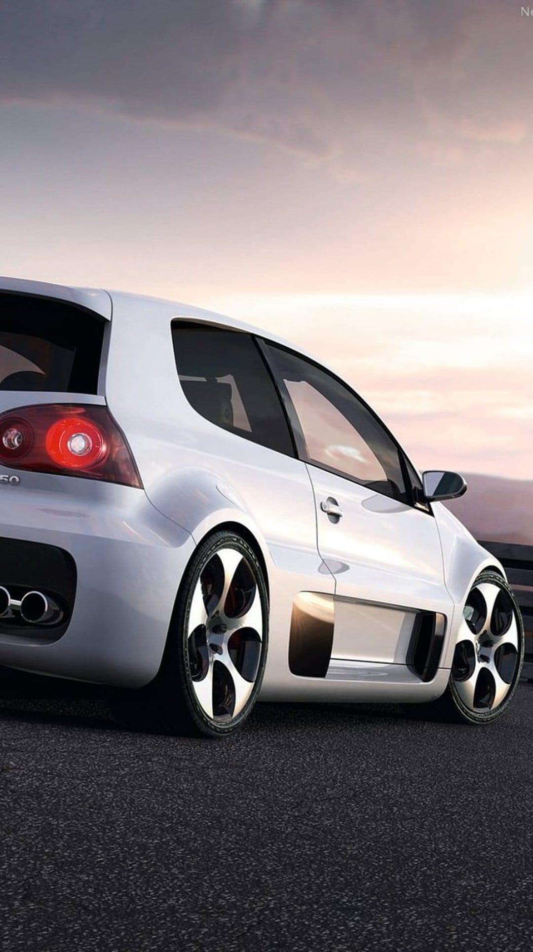 White Volkswagen Golf R32 rear profile parked on a mountain road during a hazy sunset with dual exhaust pipes.
